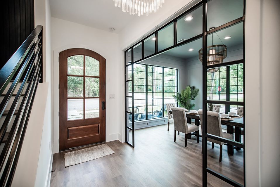Remodeled entry with a wood door, black railings, and glass interior wall